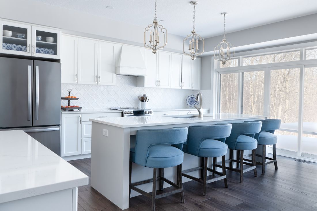Bright modern kitchen with white cabinetry and blue bar stools